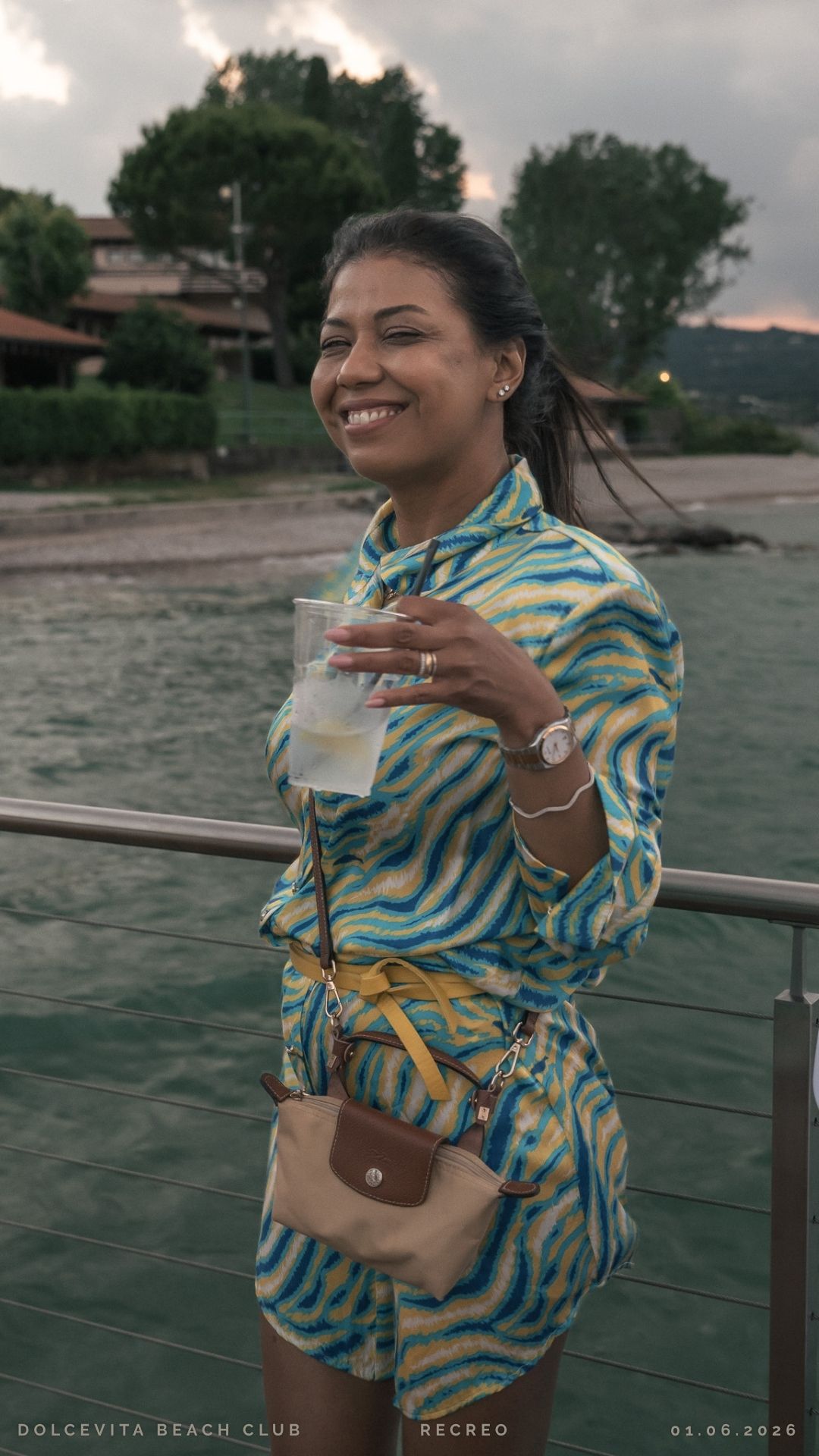 Ospite sorridente con drink al tramonto