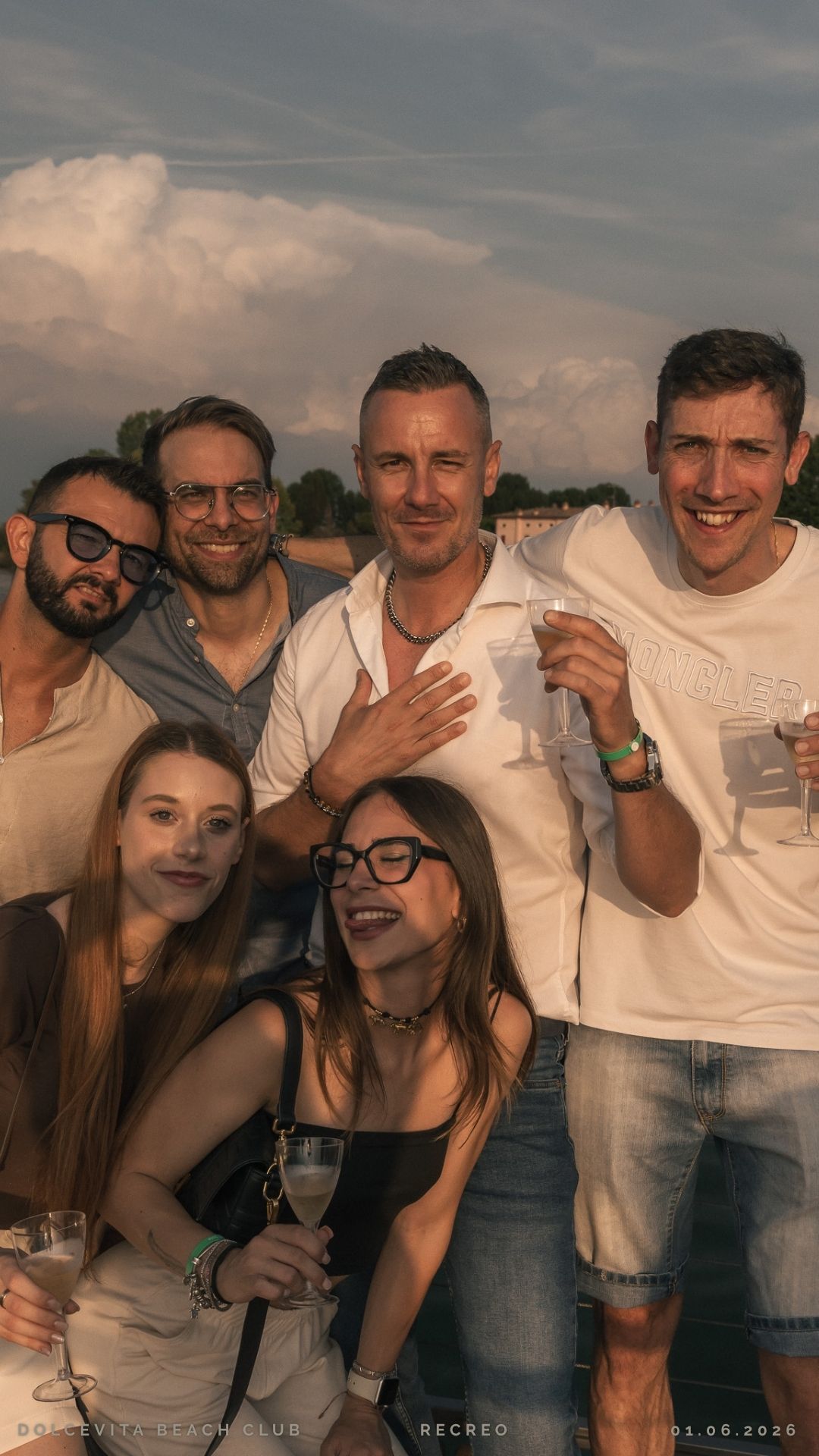 Gruppo di amici posa con calici al tramonto
