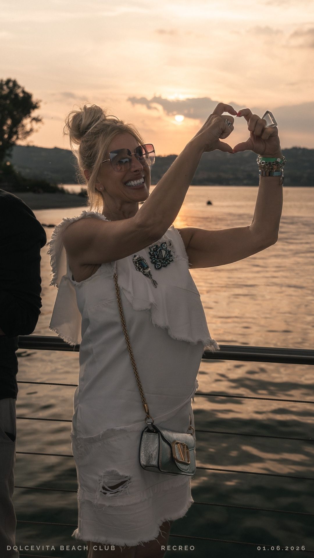 Ospite forma un cuore con le mani al tramonto